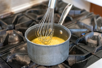 Home made healing tea is heating on the stove top while whisking the ingredients together.