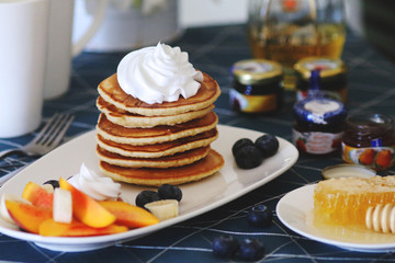 Breakfast pancakes served with honey and fruits