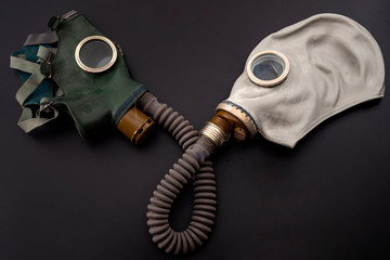 Codependent relationship, negative emotions, hazardous affair and toxic love concept with two gas masks connected on the same hose to represent codependency isolated on dark background - obrazy, fototapety, plakaty