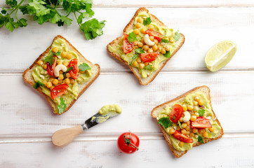Vegan sandwich with avocado, nuts, vegetables and olive oil on white wooden table
