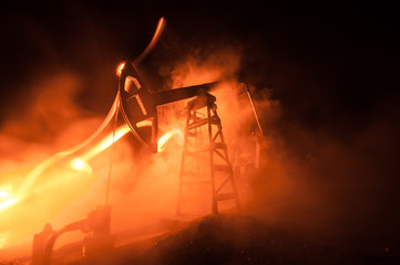 Oil pump and oil refining factory at night with fog and backlight. Energy industrial concept. Selective focus.