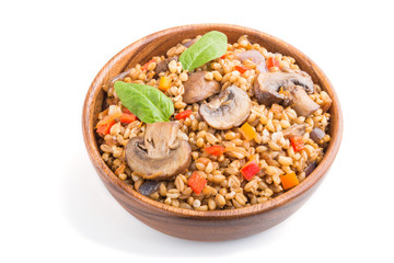 Spelt (dinkel wheat) porridge with vegetables and mushrooms in wooden bowl isolated on white background. Side view, close up.