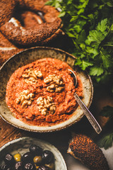 Turkish traditional spicy smoked red pepper paste with walnuts, simit bagels, fresh parsley and olives over breakfast table. Typical Turkish breakfast dish