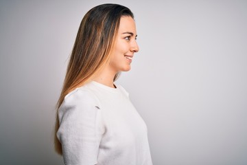 Young beautiful blonde woman with blue eyes wearing casual t-shirt over white background looking to side, relax profile pose with natural face with confident smile.