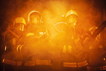 Group of professional firefighters wearing full equipment, oxygen masks, and emergency rescue...