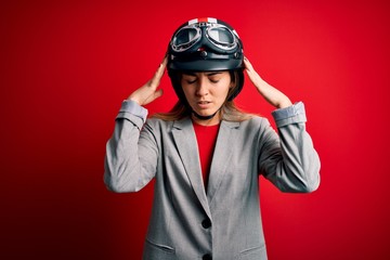 Young beautiful blonde motorcyclist woman wearing motorcycle helmet over red background with hand...