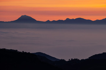 Amanecer colorido con siluetas de montañas. Mar de nubes