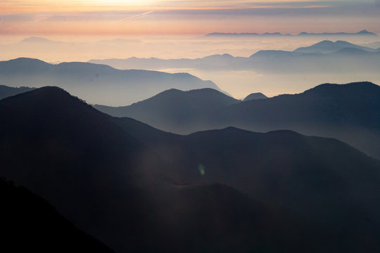 Atardecer amanecer en paisaje con siluetas de monta&ntilde;as, bruma y nubes