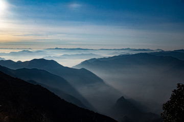 Atardecer amanecer en paisaje con siluetas de montañas, bruma y nubes