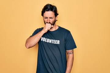 Young handsome hispanic volunteer man wearing volunteering t-shirt as social care feeling unwell and coughing as symptom for cold or bronchitis. Health care concept.