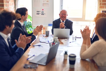 Group of business workers smiling happy and confident in a meeting. Working together looking at presentation using board and laptop applauding at the office.