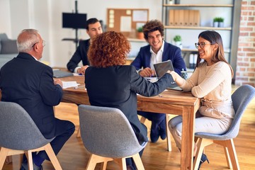 Group of business workers smiling happy and confident in a meeting. Speaking with smile on face working together shaking hands for agreement at the office.
