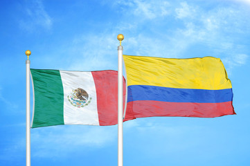 Mexico and Colombia two flags on flagpoles and blue cloudy sky