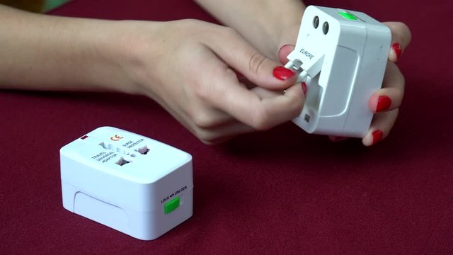 Beautiful hands of girl showing how to use universal electric socket plug adapters for travel. Used to connect to different electrical outlets worldwide. 4K.