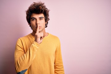 Young handsome man wearing yellow casual t-shirt standing over isolated pink background asking to be quiet with finger on lips. Silence and secret concept.