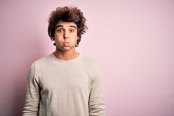 Obraz premium Young handsome man wearing casual t-shirt standing over isolated pink background puffing cheeks with funny face. Mouth inflated with air, crazy expression.