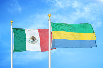 Mexico and Gabon two flags on flagpoles and blue cloudy sky