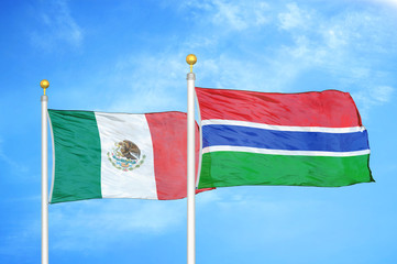 Mexico and Gambia two flags on flagpoles and blue cloudy sky
