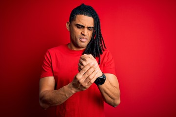 Young handsome african american afro man with dreadlocks wearing red casual t-shirt Suffering pain on hands and fingers, arthritis inflammation
