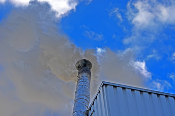 black smog from high industrial pipe with silver insolation on blue sky with white clouds,,...