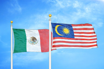 Mexico and Malaysia two flags on flagpoles and blue cloudy sky