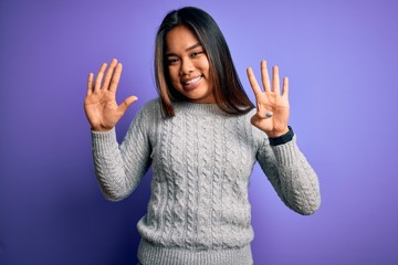 Young beautiful asian girl wearing casual sweater standing over isolated purple background showing and pointing up with fingers number nine while smiling confident and happy.