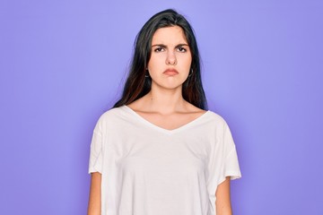 Fototapeta premium Young beautiful brunette woman wearing casual white t-shirt over purple background depressed and worry for distress, crying angry and afraid. Sad expression.