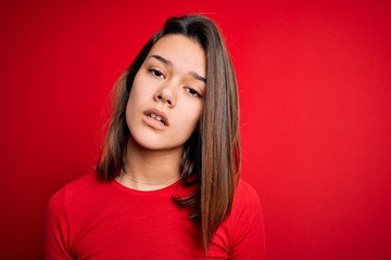 Fototapeta premium Young beautiful brunette girl wearing casual t-shirt over isolated red background looking sleepy and tired, exhausted for fatigue and hangover, lazy eyes in the morning.