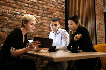 Three young business colleagues having a meeting in a modern cafe in the late evening hours. Successfull startup team brainstorming after work hours.