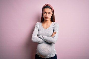 Young beautiful teenager girl pregnant expecting baby over isolated pink background skeptic and...