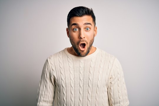 Young handsome man wearing casual sweater standing over isolated white background afraid and shocked with surprise expression, fear and excited face.