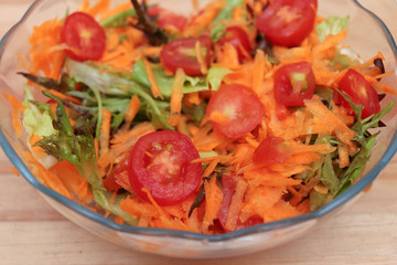 Salad bowl with tomatos, carrots and leaves