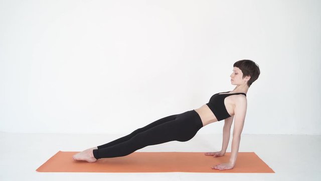 Young woman doing yoga bridge pose purvottanasana in white studio