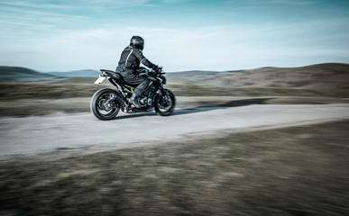 Fototapeta na wymiar Biker Riding Sport Motorcycle on Rural Road