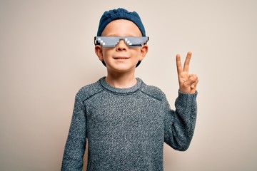 Young little caucasian kid wearing internet meme thug life glasses over isolated background smiling with happy face winking at the camera doing victory sign. Number two.
