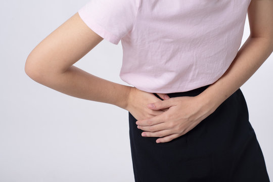 Closeup young sick woman with hands holding pressing her crotch lower abdomen over white background. Medical or gynecologicals or Cystitis problems, healthcare concept