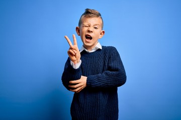 Young little caucasian kid with blue eyes wearing winter sweater over blue background smiling with...