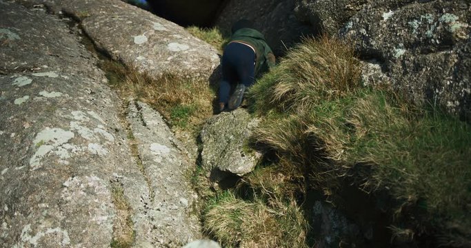 Little preschooler climbing rocks on the moor in winter