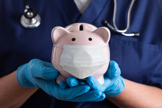 Doctor or Nurse Wearing Surgical Gloves Holding Piggy Bank Wearing Medical Face Mask