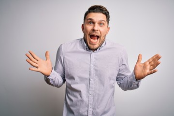 Fototapeta premium Young business man with blue eyes standing over isolated background celebrating crazy and amazed for success with arms raised and open eyes screaming excited. Winner concept