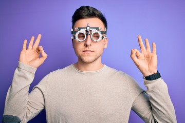 Young handsome caucasian man wearing optometrical glasses over purple background relax and smiling with eyes closed doing meditation gesture with fingers. Yoga concept.