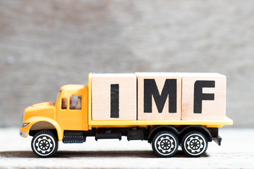 Truck hold letter block in word IMF (abbreviation of International Monetary Fund) on wood background