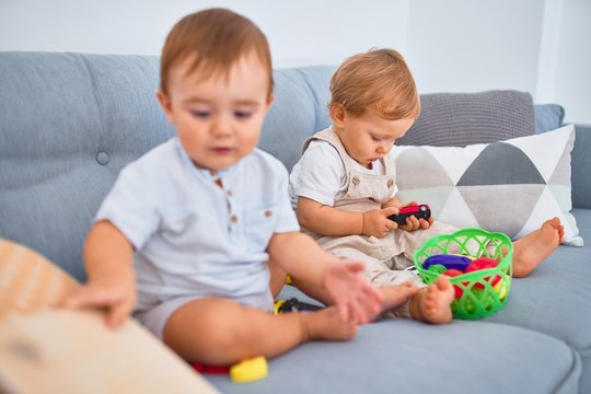 Beautiful toddlers sitting on the sofa playing with toys at home