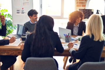 Group of business workers smiling happy and confident. Working together with smile on face  using laptop and speaking at the office