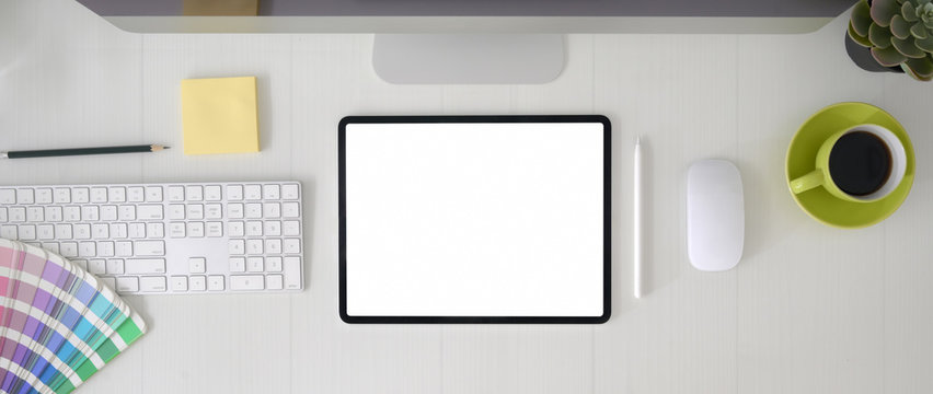 Top view of graphic designer workspace with blank screen tablet, computer device and designer supplies