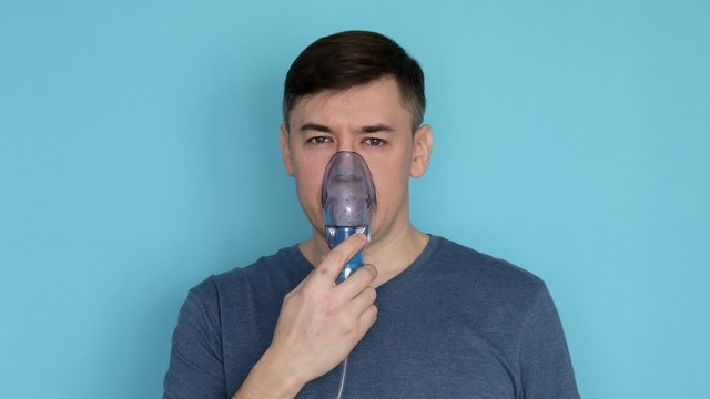 Portrait of man using nebulizer with breathing mask inhaling medication
