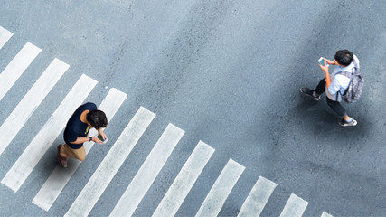 Human life in Social distance. Aerial top view with blur man with smartphone walking converse of other people at pedestrian crosswalk on grey pavement street road with empty space.