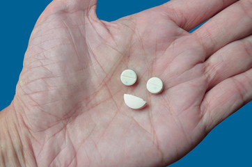 Drug dependence, illustrated by pills arranged to look like happy face, implying depending on drug or substance to feel well. Blue background represents "feeling blue"