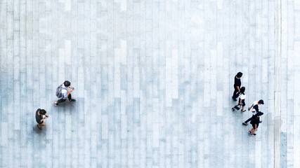 Obraz premium Human life in Social distance. Aerial top view with blur man with smartphone and group of people walking at pedestrian crosswalk on grey pavement street road with empty space.