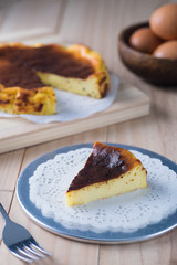 Delicious homemade burnt cheesecake on wooden table. Slice of cake taken out, egg decoration